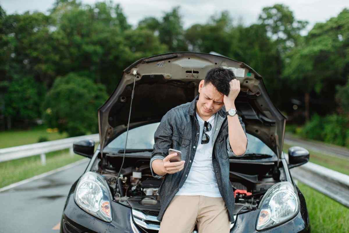 Automobilista infastidito con auto in panne